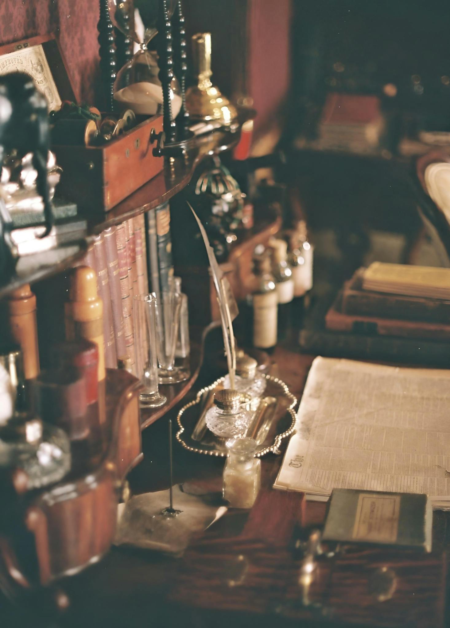 A charming vintage desk filled with antique books and decor items in soft lighting.