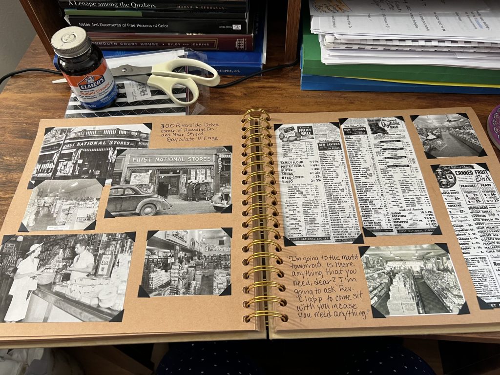 A desk workspace showing a scrapbook of historical research, vintage photos, and newspaper clippings for a novel project.