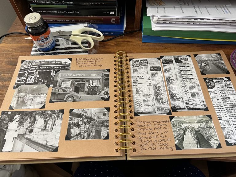A desk workspace showing a scrapbook of historical research, vintage photos, and newspaper clippings for a novel project.
